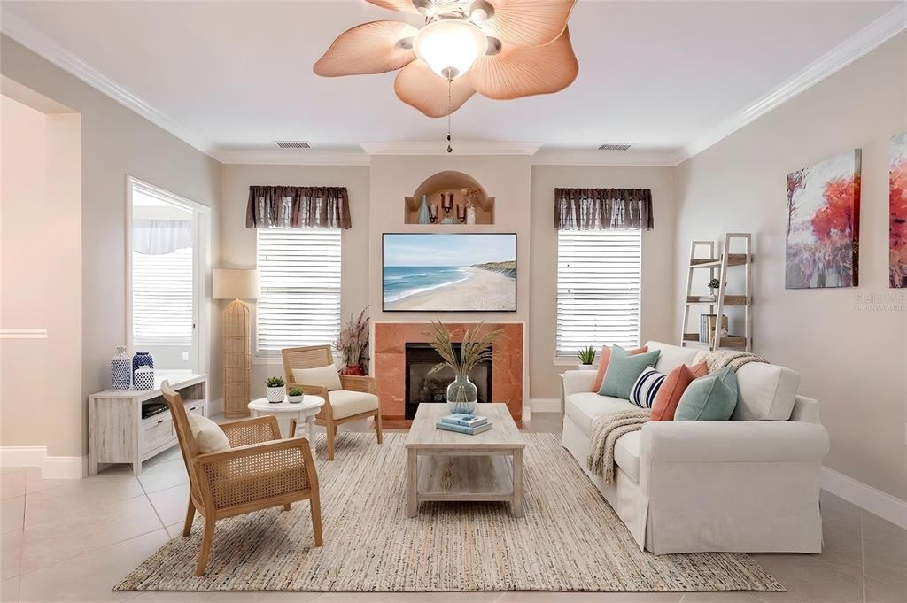 A living room features a fireplace with a mounted television, a sofa, and two chairs — 2749 VIA CIPRIANI UNIT 1010B, CLEARWATER, FL
