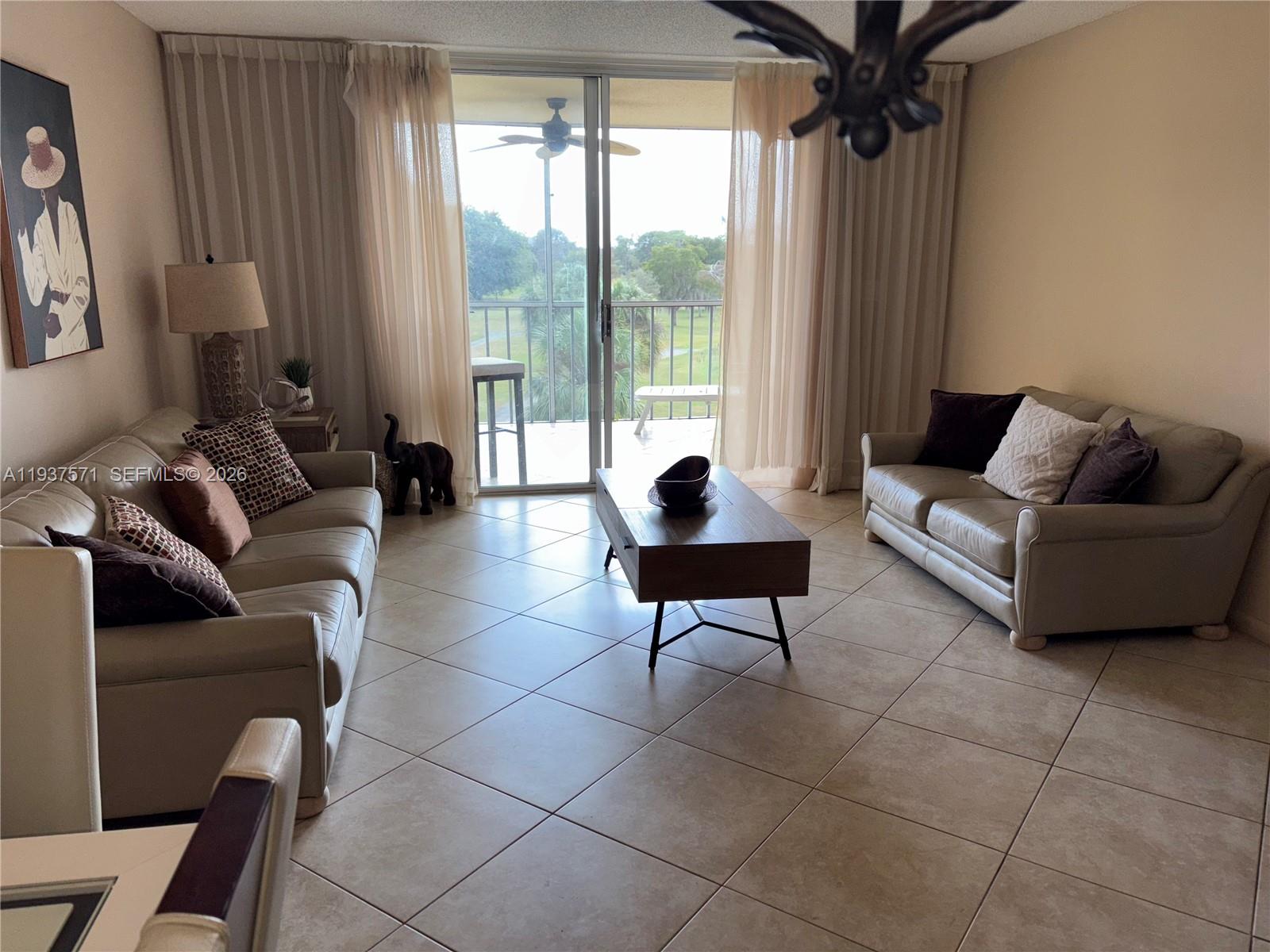 A living room features two beige sofas, a coffee table, and a sliding glass door — 7690 NW 18th St # 408, Margate FL 33063, MARGATE, FL