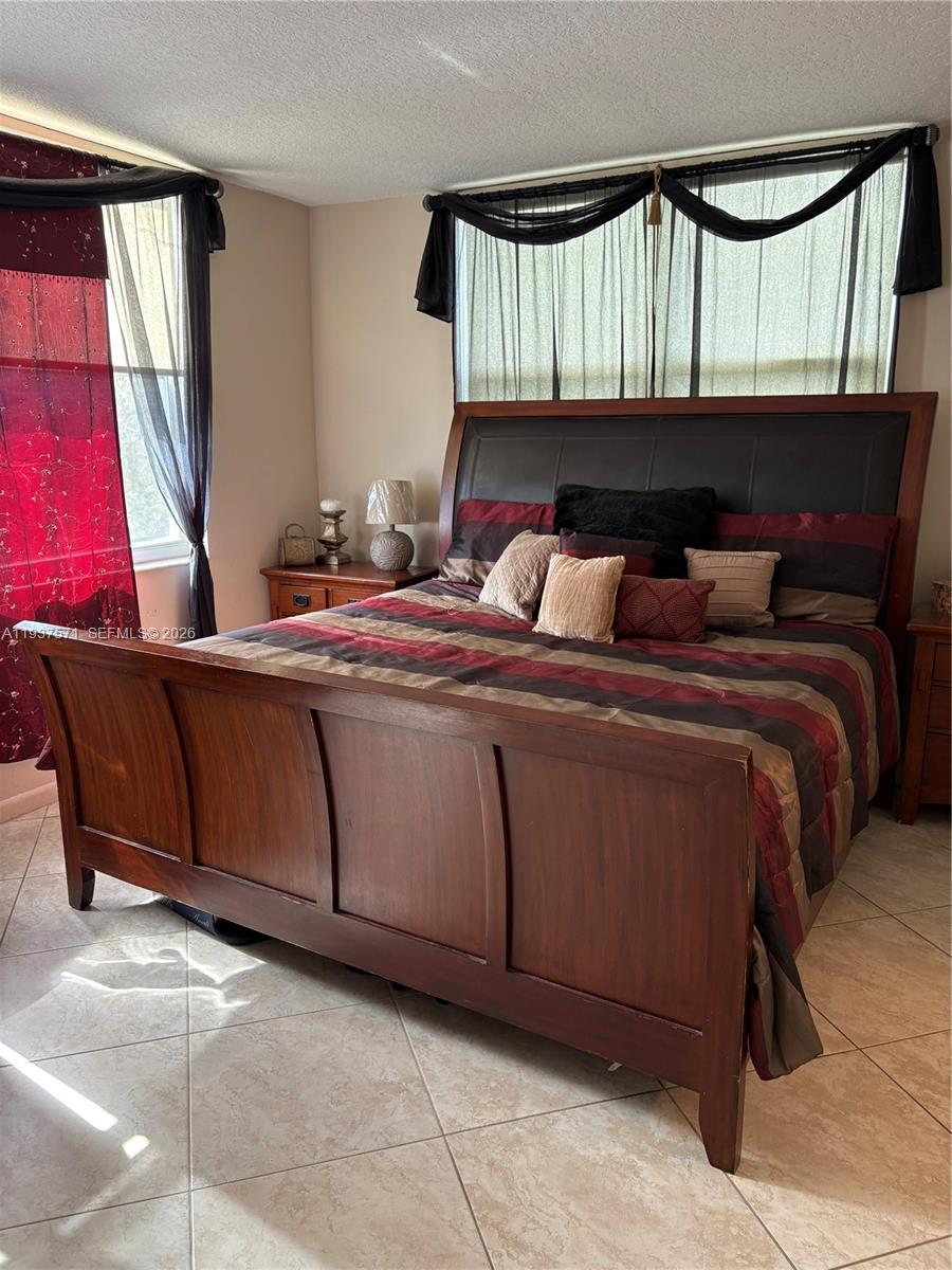 A bedroom features a wooden sleigh bed, tiled floors, and dark window treatments — 7690 NW 18th St # 408, Margate FL 33063, MARGATE, FL