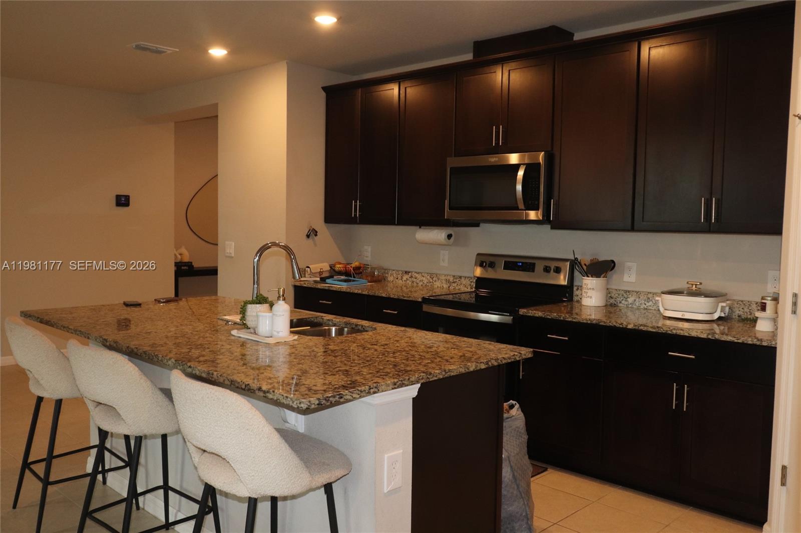 A kitchen features dark wood cabinets, granite countertops, a center island, and stainless steel appliances — 920 CAMBRIDGE DR, Winter Haven FL 33881, WINTER HAVEN, FL