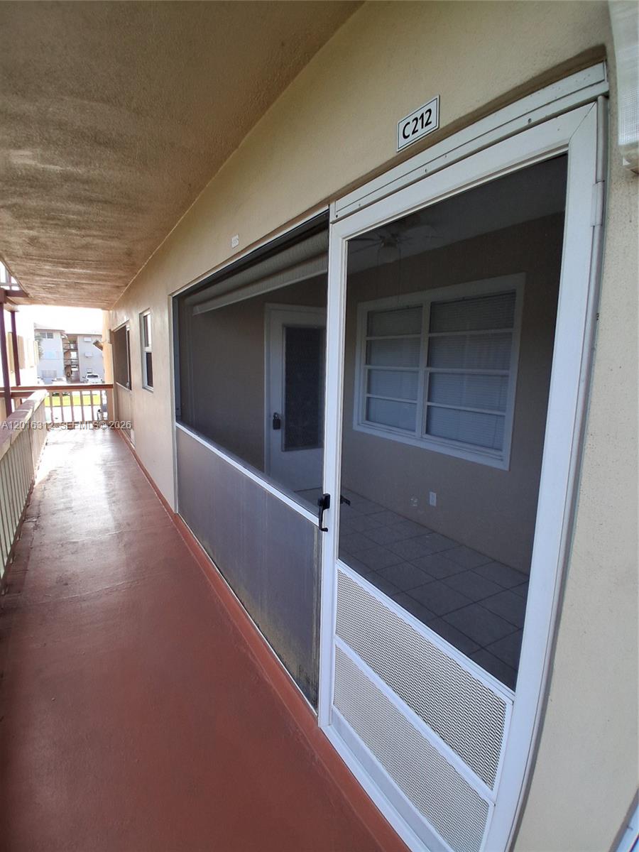 A screened-in balcony with a tiled floor and a white door leads to unit C212 — 5300 Washington St # C212, Hollywood FL 33021, HOLLYWOOD, FL