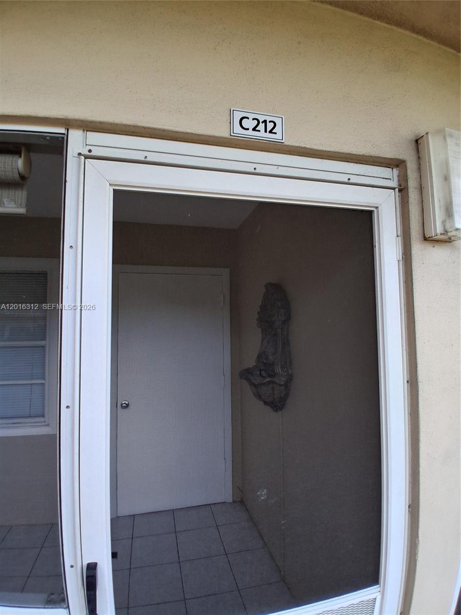 A white screen door leads to an entryway with a wall-mounted decorative fountain — 5300 Washington St # C212, Hollywood FL 33021, HOLLYWOOD, FL