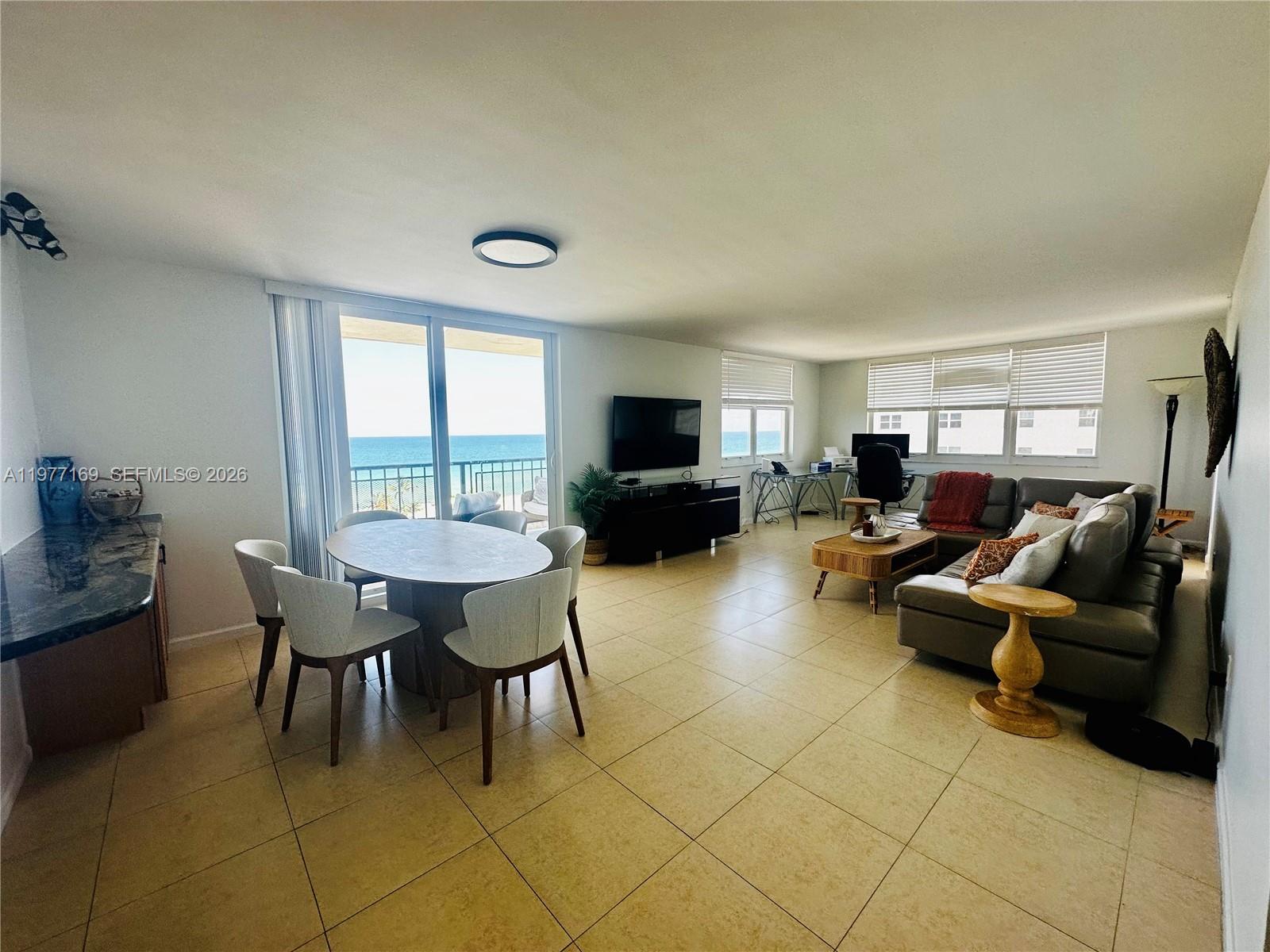 An open-concept living and dining area features tile flooring, a balcony, and ocean views — 1501 S Ocean Dr # 1006, Hollywood FL 33019, HOLLYWOOD, FL