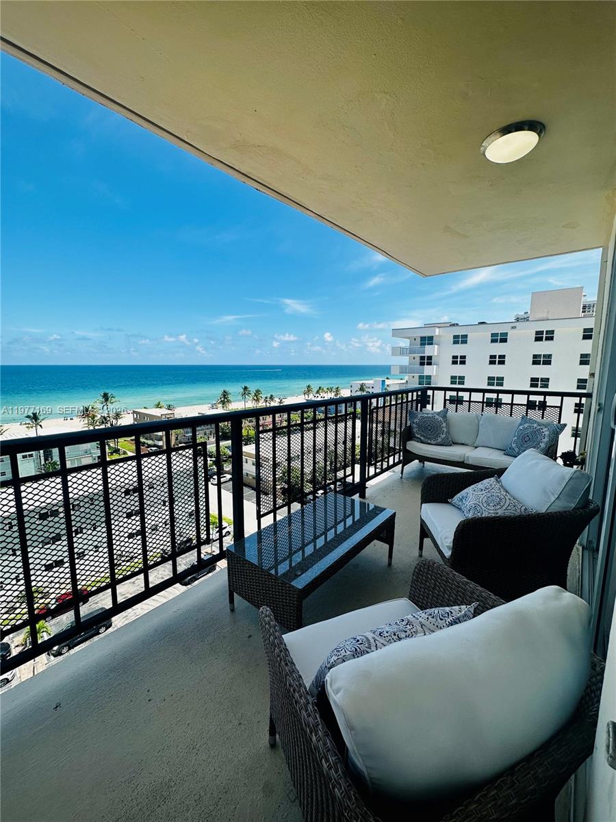 A balcony with wicker furniture overlooks a beach and the ocean — 1501 S Ocean Dr # 1006, Hollywood FL 33019, HOLLYWOOD, FL