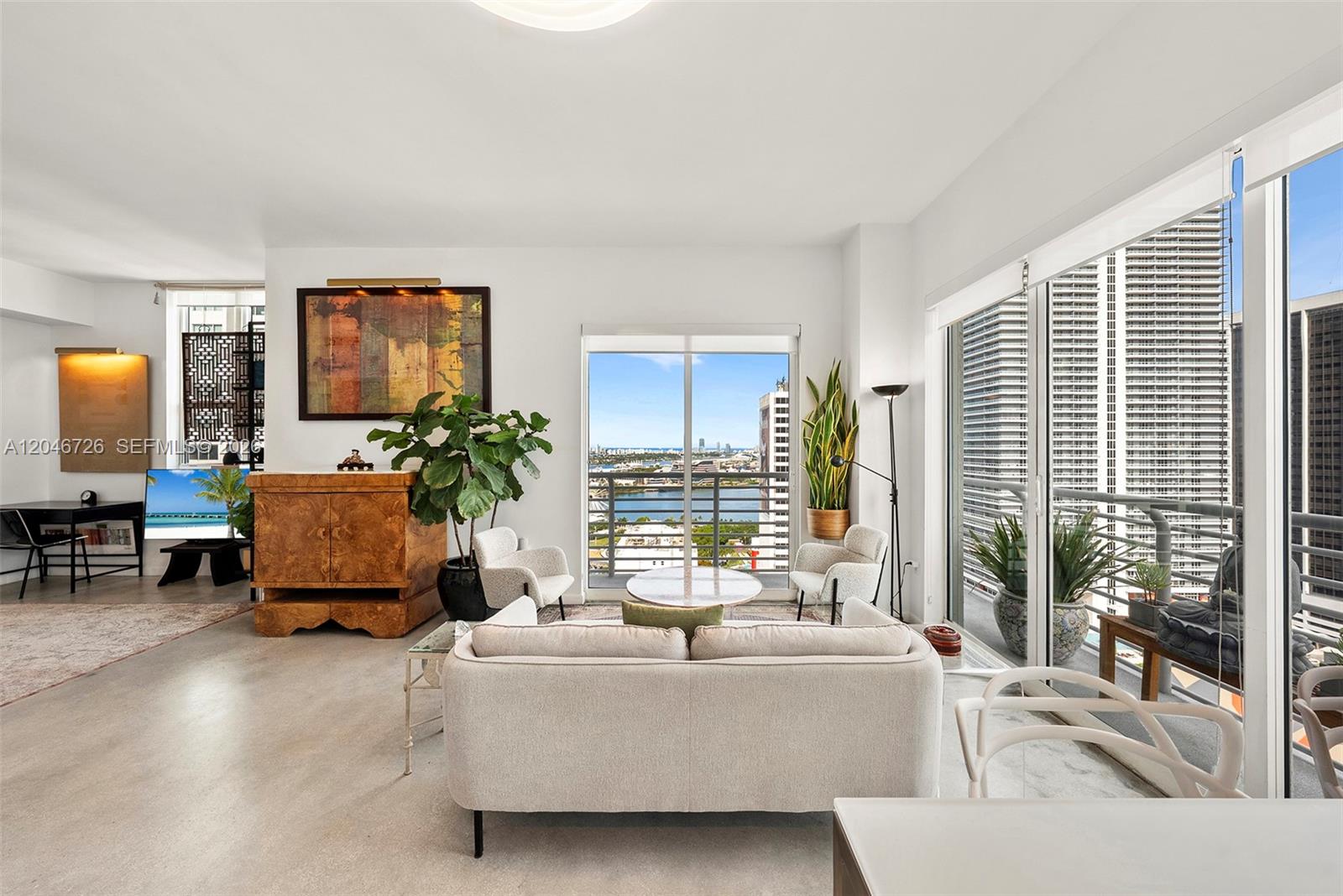 A bright living room features concrete floors, modern furniture, and a balcony with city views — 133 NE 2nd Ave # 2702, Miami FL 33132, MIAMI, FL