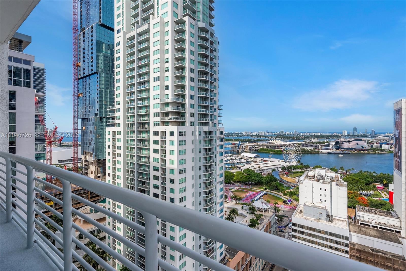 A high-rise balcony view overlooks a city skyline, a Ferris wheel, and a bay — 133 NE 2nd Ave # 2702, Miami FL 33132, MIAMI, FL
