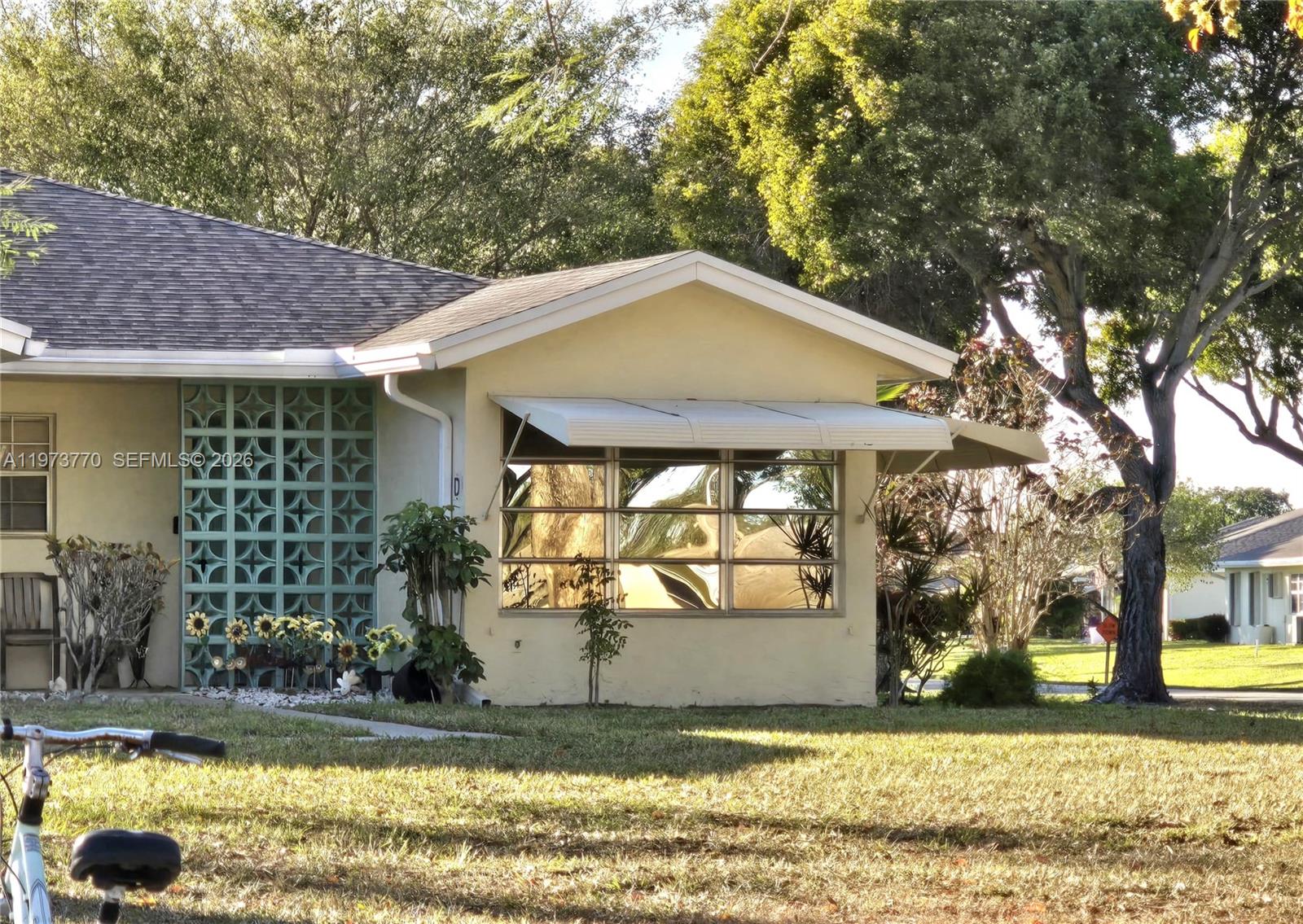 The exterior of a single-story house features a decorative teal screen and a window awning — 5162 Lakefront Blvd # D, Delray Beach FL 33484, DELRAY BEACH, FL