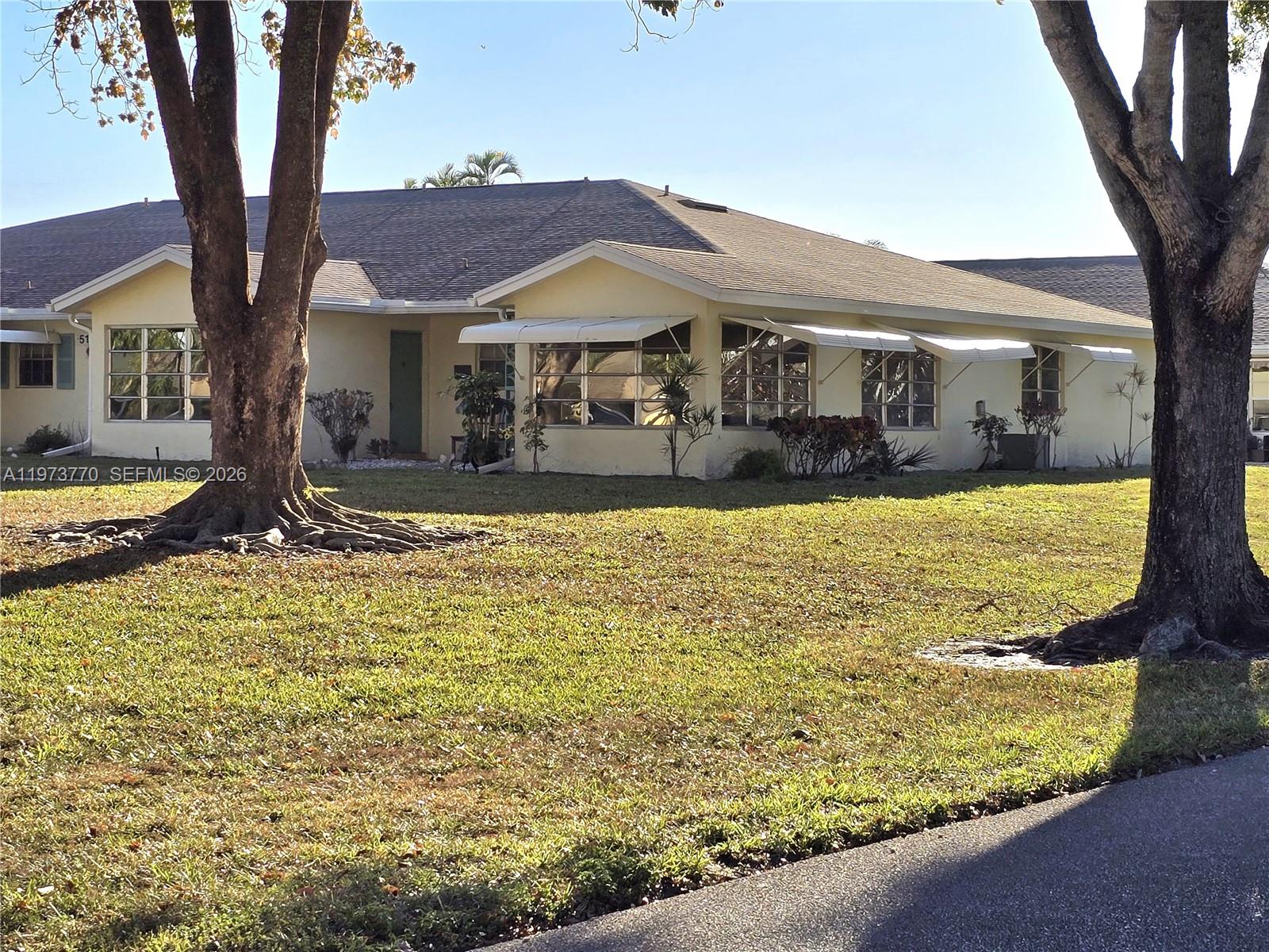 A pale yellow single-story house features a large lawn and two prominent shade trees — 5162 Lakefront Blvd # D, Delray Beach FL 33484, DELRAY BEACH, FL