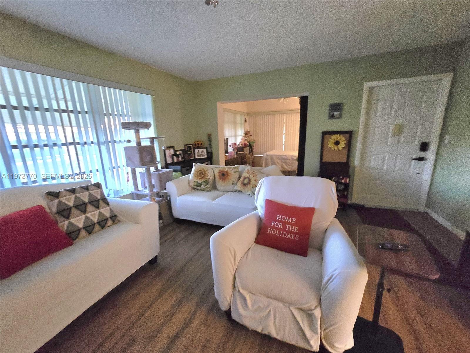 A living room features white sofas, a recliner, sunflower pillows, and light green walls — 5162 Lakefront Blvd # D, Delray Beach FL 33484, DELRAY BEACH, FL