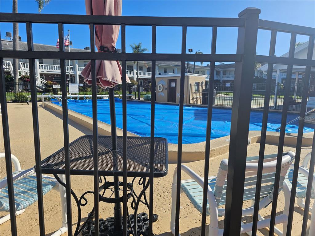 A black metal fence overlooks a swimming pool covered with a blue tarp — 4747 AZALEA DRIVE UNIT 125, NEW PORT RICHEY, FL
