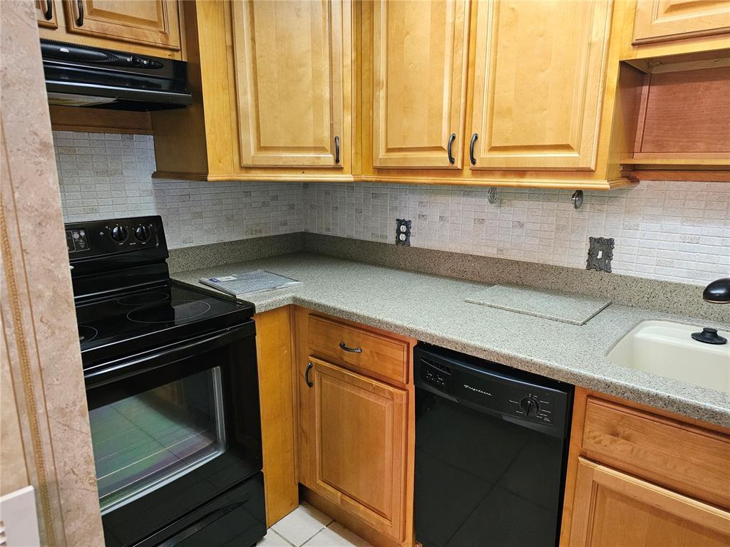 A kitchen features light wood cabinets, black appliances, and a speckled gray countertop — 4747 AZALEA DRIVE UNIT 125, NEW PORT RICHEY, FL