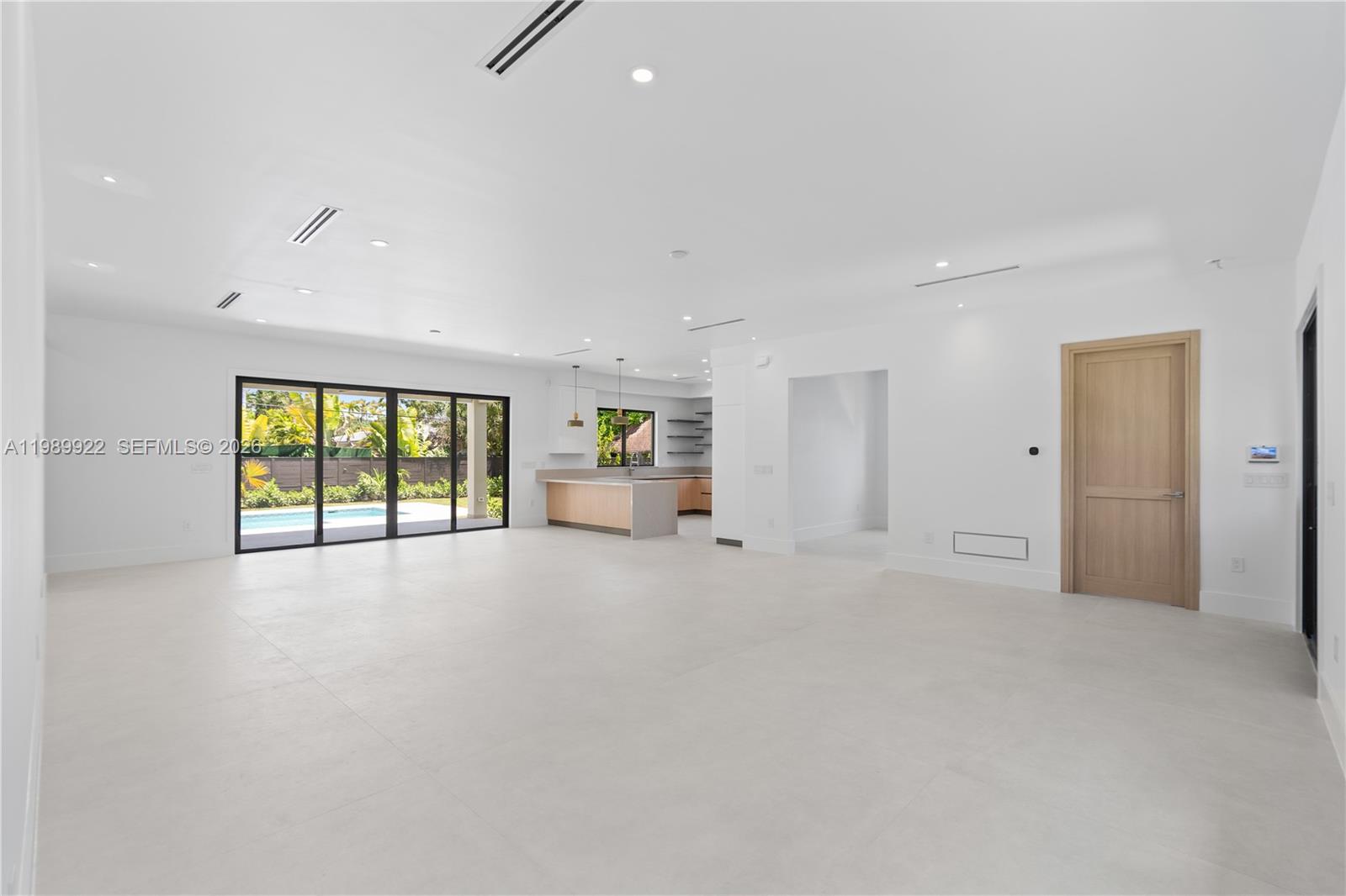 A spacious, minimalist living area features white tile floors, recessed lighting, and a modern kitchen — 6221 SW 60th St, South Miami FL 33143, SOUTH MIAMI, FL