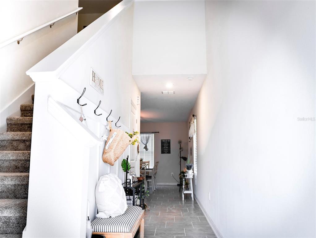 A bright entryway features a carpeted staircase, a bench with hooks, and tile flooring — 2949 MULLER OAK LOOP, OCOEE, FL