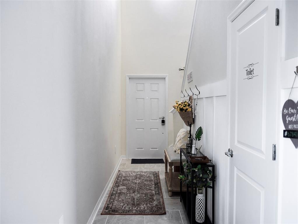 A bright entryway features a white front door, tile flooring, a bench, and a console table — 2949 MULLER OAK LOOP, OCOEE, FL