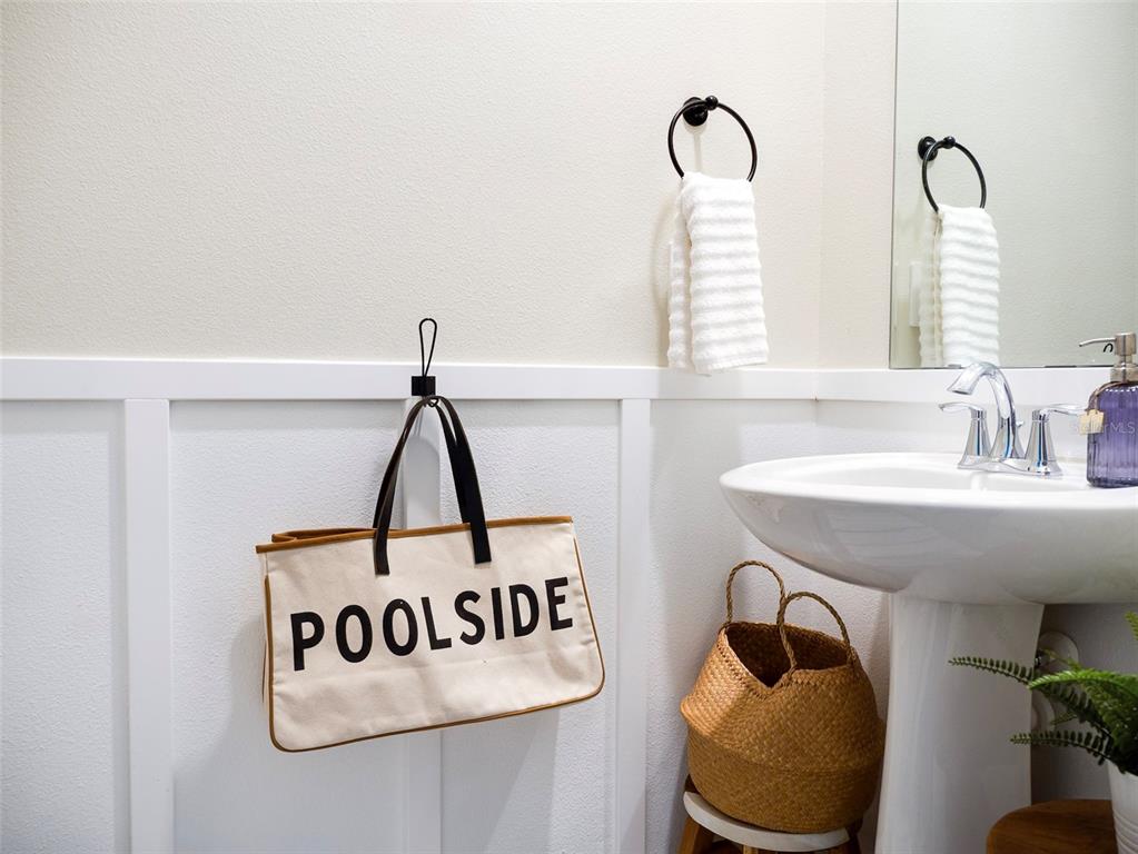A bathroom features a pedestal sink, a hanging poolside bag, and white wainscoting — 2949 MULLER OAK LOOP, OCOEE, FL