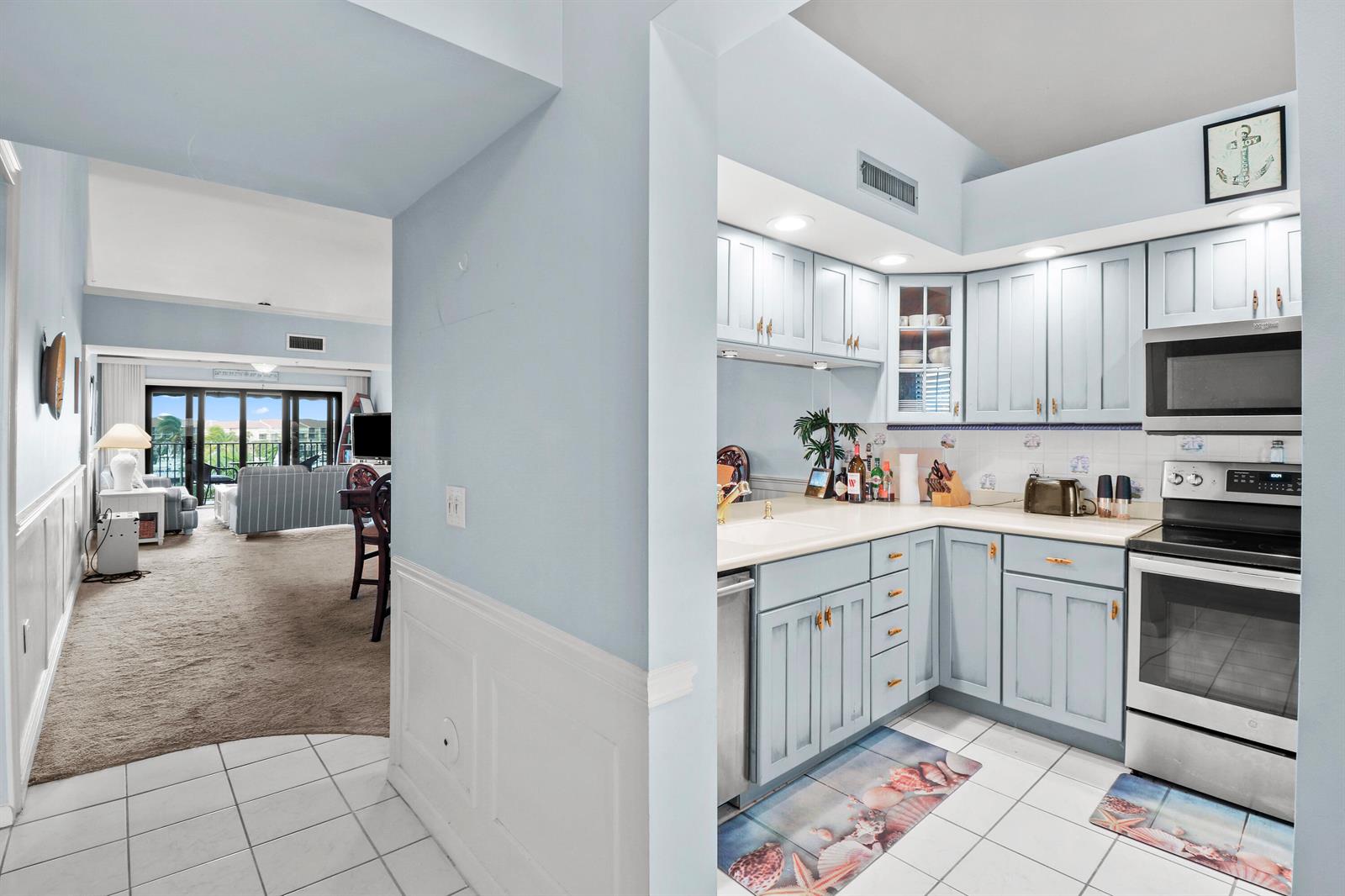 A kitchen with light blue cabinets and white tile floors opens to a living area — 901 Seafarer Circle # 503, Jupiter FL 33477, JUPITER, FL