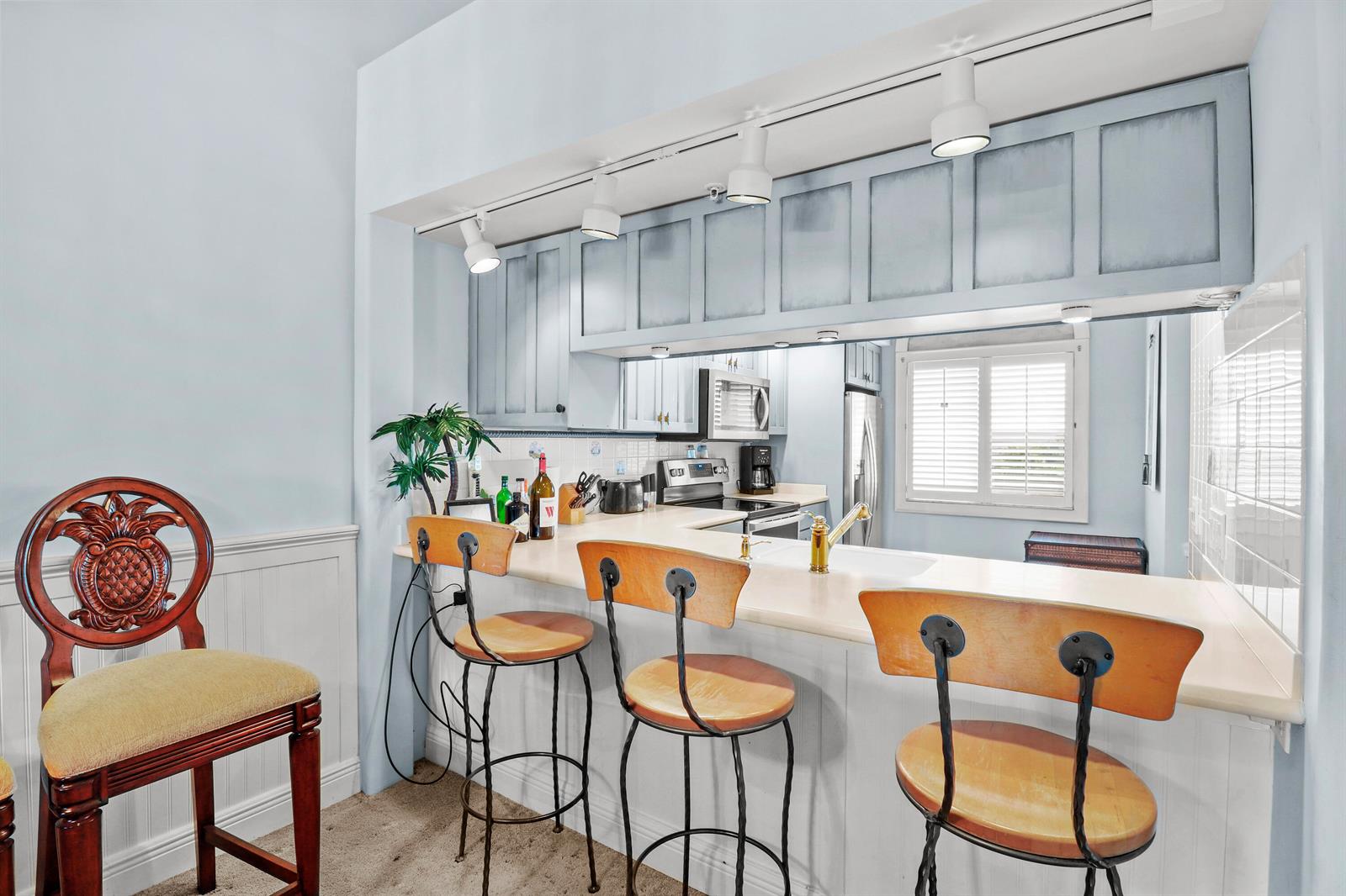 A kitchen features a breakfast bar with three stools and a separate ornate wooden chair — 901 Seafarer Circle # 503, Jupiter FL 33477, JUPITER, FL