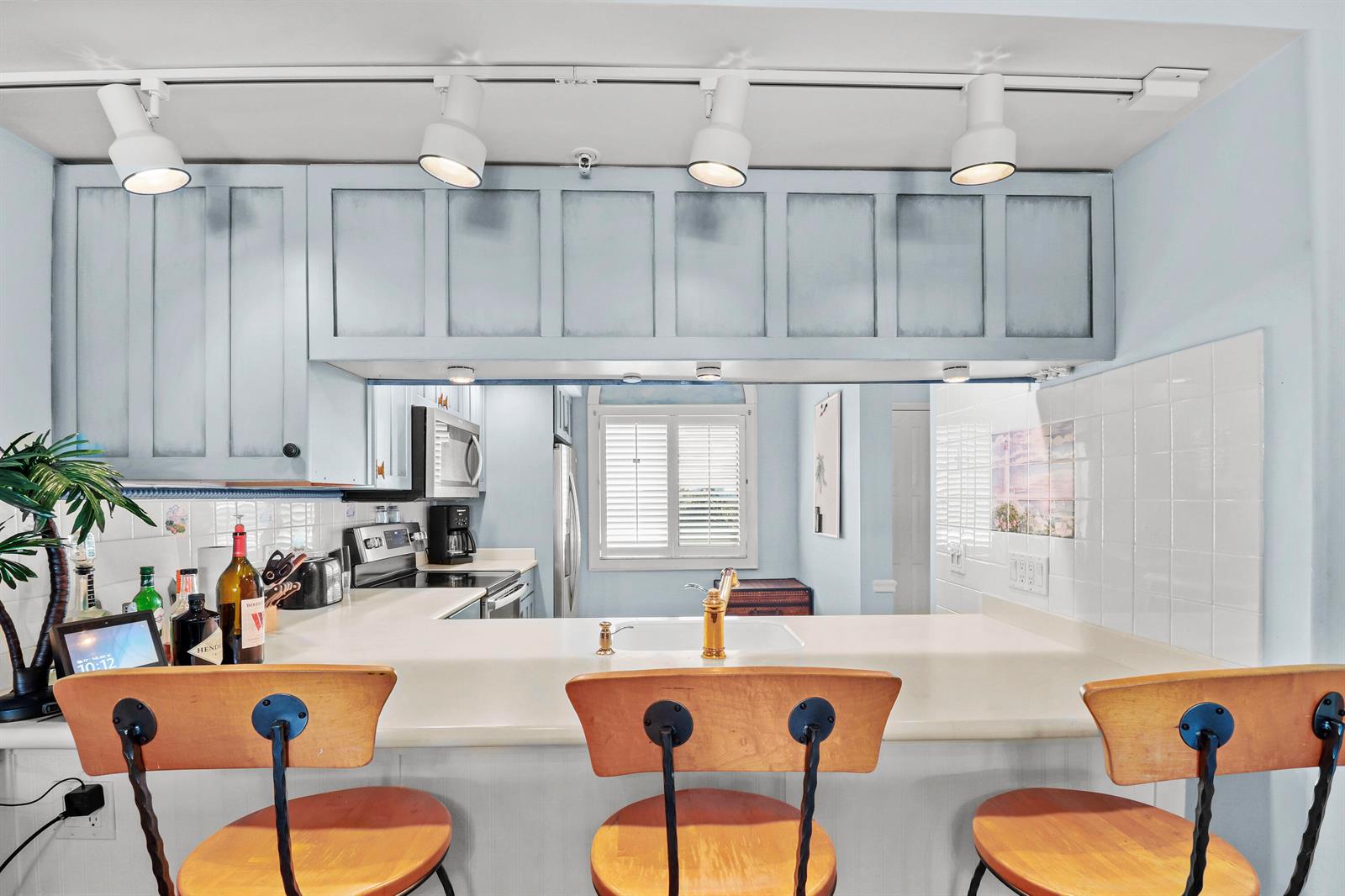 A kitchen features a breakfast bar with three wooden stools and light blue cabinetry — 901 Seafarer Circle # 503, Jupiter FL 33477, JUPITER, FL