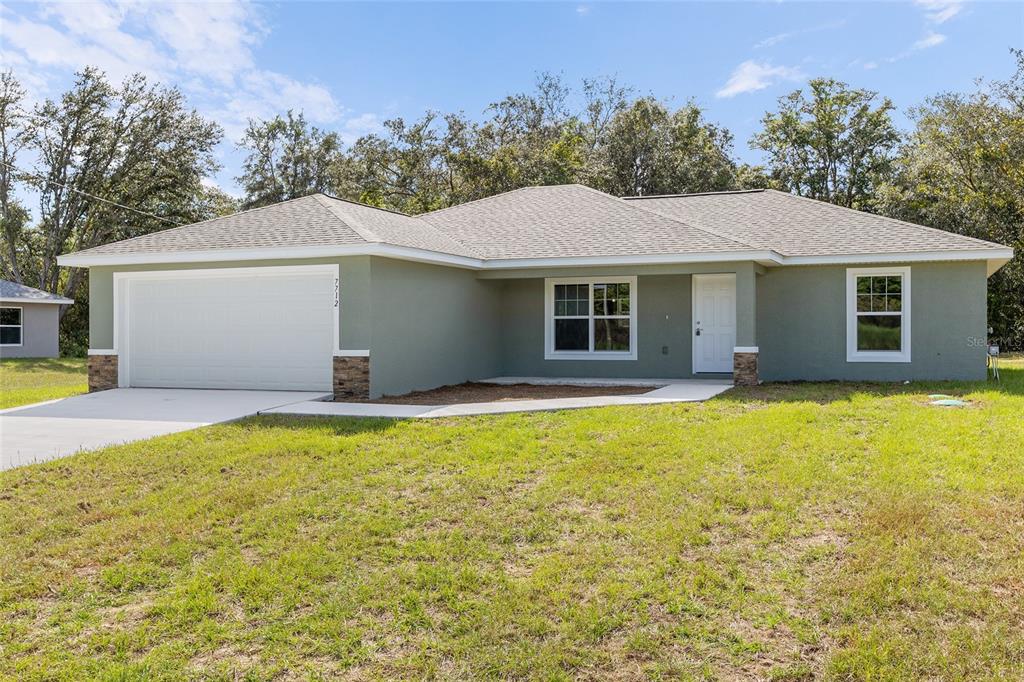 An open-concept living and dining area features light wood flooring, neutral walls, and a kitchen — 5676 N SUMMERFIELD POINT, CITRUS SPRINGS, FL
