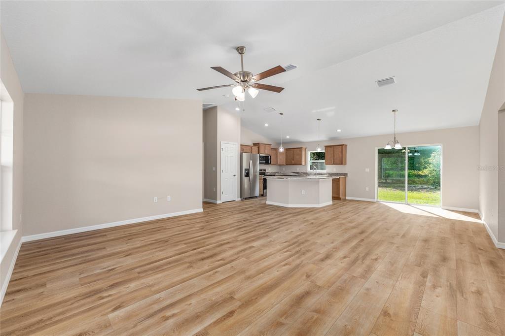 An open-concept dining area, living room, and kitchen with light wood flooring and neutral walls — 5676 N SUMMERFIELD POINT, CITRUS SPRINGS, FL