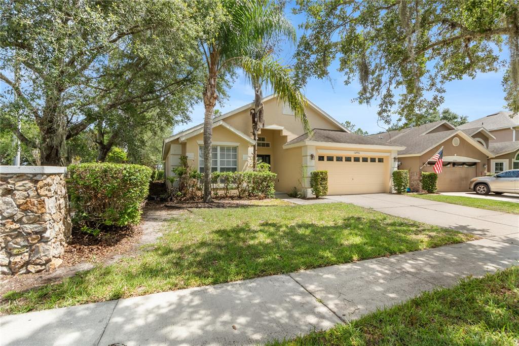 A single-story suburban house with a tan exterior, a two-car garage, and a palm tree — 10990 ELIOTTI STREET, ORLANDO, FL