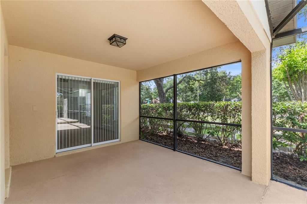 A covered patio features a concrete floor, sliding glass doors, and black-framed screen walls — 10990 ELIOTTI STREET, ORLANDO, FL