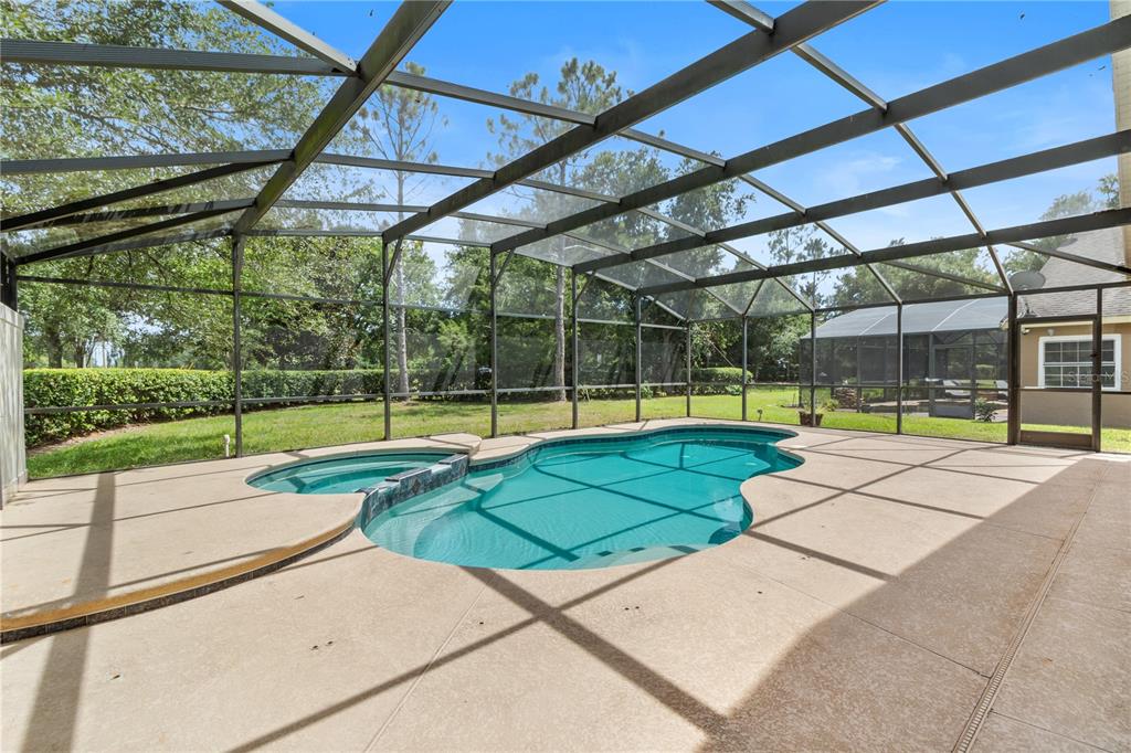A screened-in patio features a swimming pool with an attached spa and concrete decking — 10990 ELIOTTI STREET, ORLANDO, FL