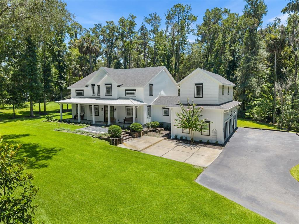 A two-story white farmhouse with a wrap-around porch sits on a large grassy lawn — 994 SW 37TH PLACE ROAD, OCALA, FL