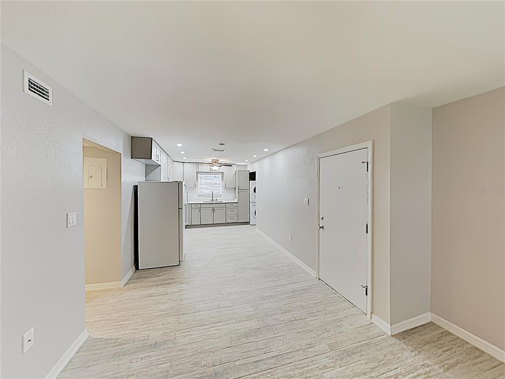 A kitchen and entryway area features light-colored tile flooring, white cabinets, and stainless steel appliances — 525 CONWAY ROAD UNIT 91, ORLANDO, FL