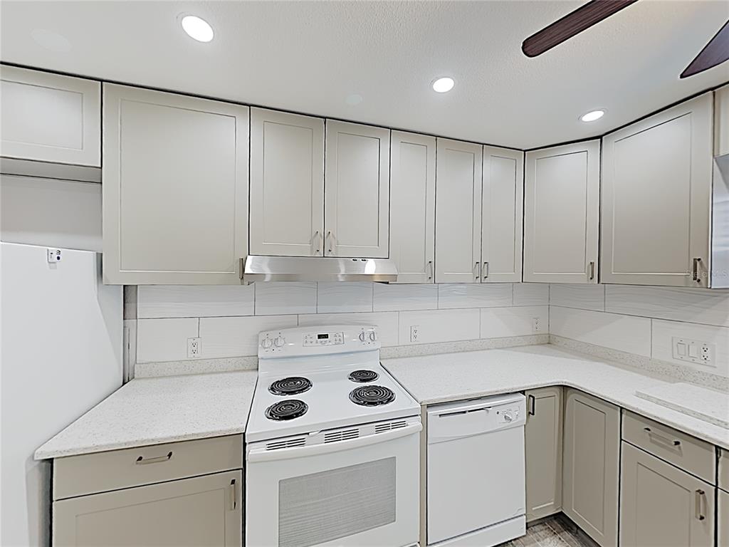 A kitchen features light gray cabinets, white countertops, a white stove, and a white dishwasher — 525 CONWAY ROAD UNIT 91, ORLANDO, FL