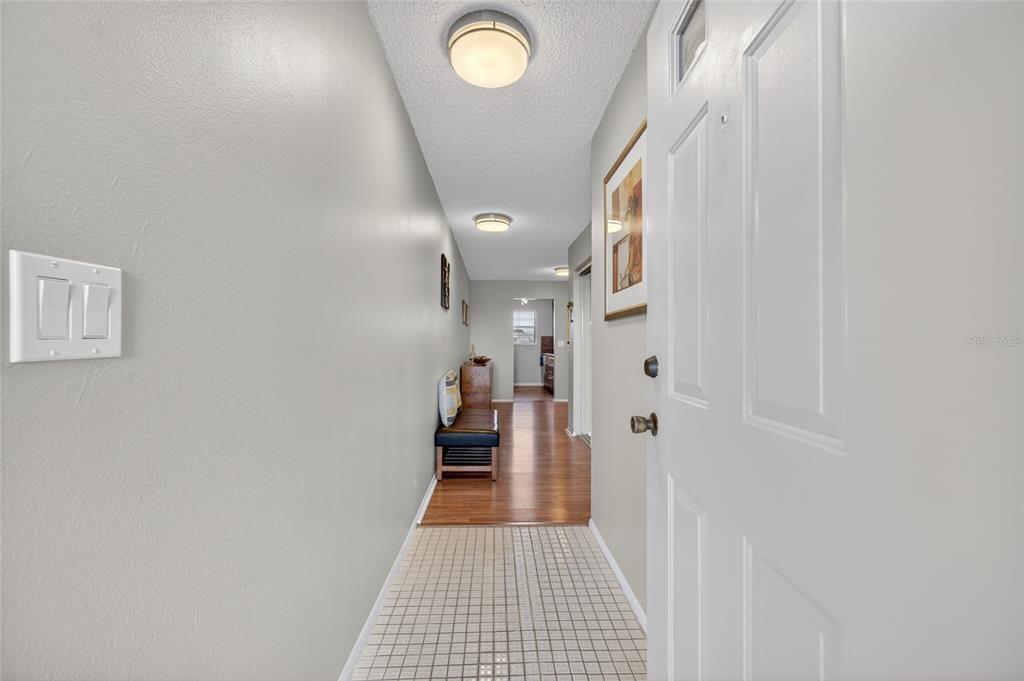 A view from an open front door into a hallway with tiled and wood flooring — 6080 80TH STREET N UNIT 409, ST PETERSBURG, FL