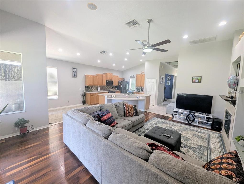 A living room with a gray sectional sofa faces a television and an open kitchen — 11236 BLACKSMITH DRIVE, TAMPA, FL