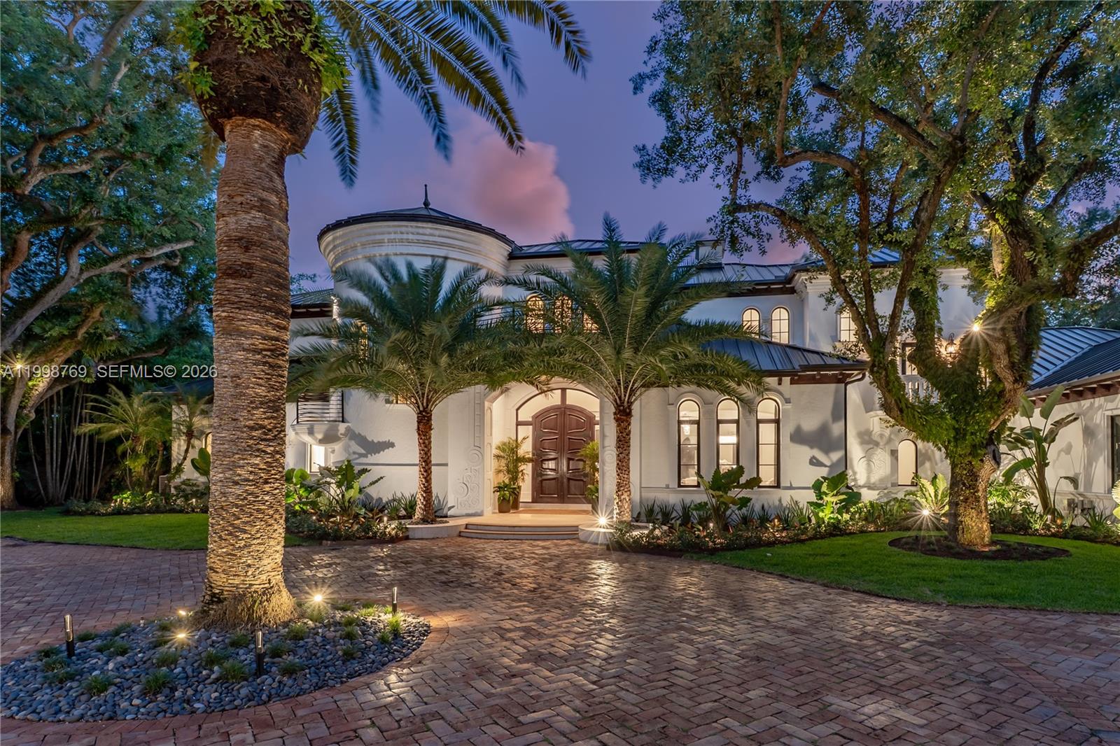 A two-story white stucco house with a turret and arched windows at dusk — 6350 SW 107th St, Pinecrest FL 33156, PINECREST, FL