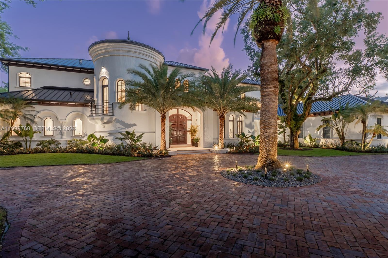 A large white Mediterranean-style house features a circular tower, arched windows, and a brick driveway — 6350 SW 107th St, Pinecrest FL 33156, PINECREST, FL