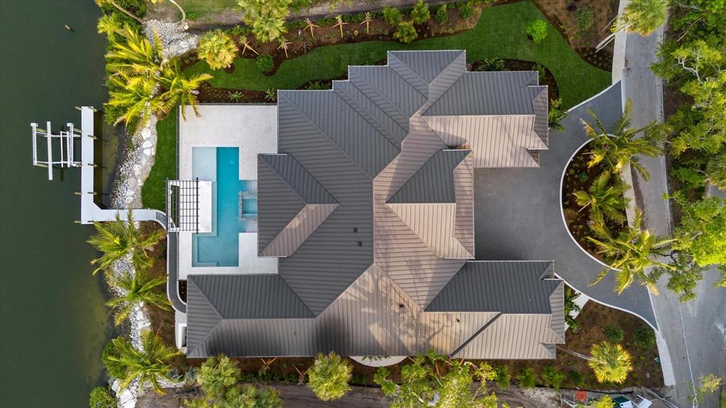An aerial view shows a house with a dark metal roof, pool, and waterfront dock — 5215 HIDDEN HARBOR ROAD, SARASOTA, FL