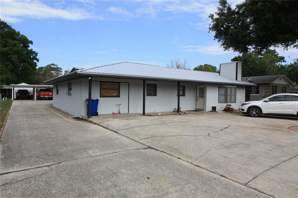 A single-story house with a white brick exterior, metal roof, and a large concrete driveway — 521 20TH STREET SW UNIT C, WINTER HAVEN, FL