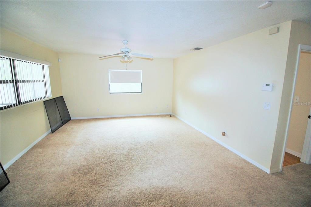 An empty room features beige carpeting, light-colored walls, a ceiling fan, and a window — 521 20TH STREET SW UNIT C, WINTER HAVEN, FL