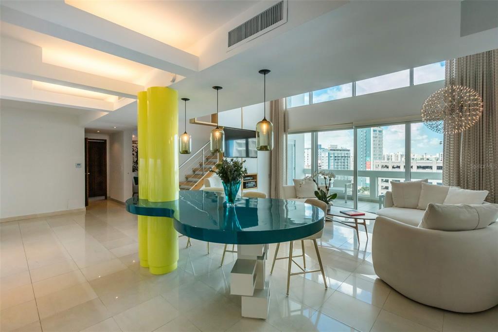 A modern living and dining area features a bright yellow pillar and a teal table — 1315 ASHFORD AVENUE AVENUE UNIT 905, SAN JUAN, PR