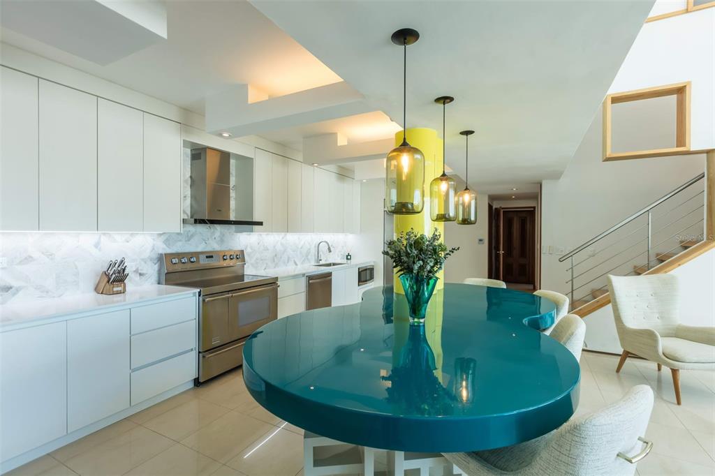 A modern kitchen features white cabinetry, a teal curved island, and three hanging glass pendants — 1315 ASHFORD AVENUE AVENUE UNIT 905, SAN JUAN, PR