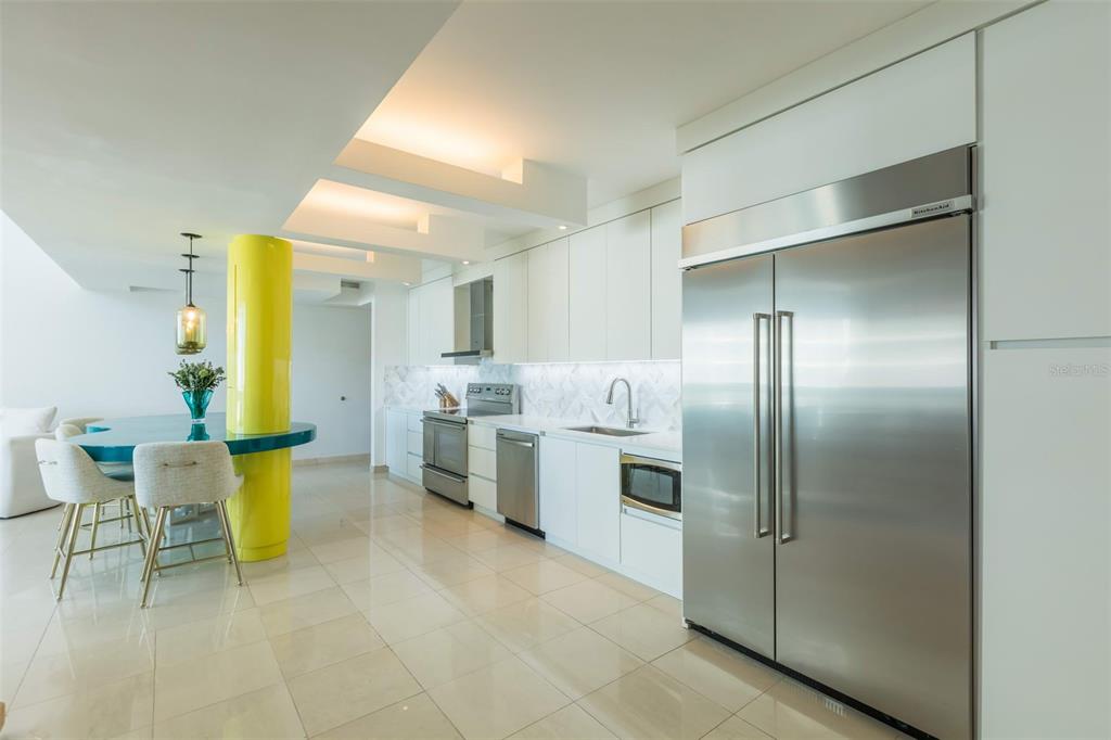 A modern kitchen features white cabinetry, stainless steel appliances, and a bright yellow structural column — 1315 ASHFORD AVENUE AVENUE UNIT 905, SAN JUAN, PR