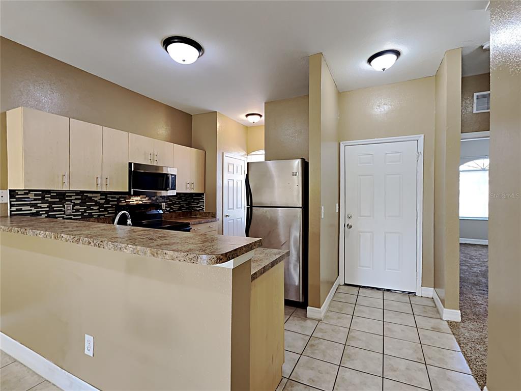 A kitchen features light wood cabinets, a breakfast bar, and stainless steel appliances — 176 OCEAN BLUFF DRIVE, POINCIANA, FL