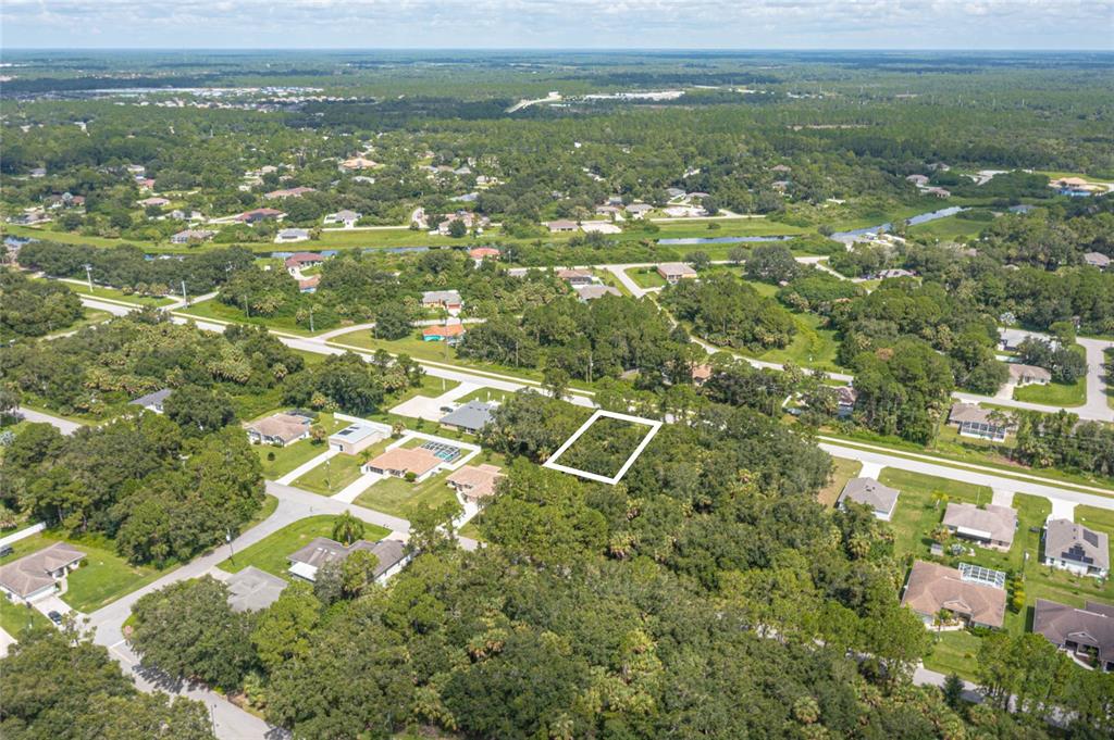 An aerial view shows a vacant, wooded residential lot outlined in white within a suburban neighborhood — E PRICE BOULEVARD LOT 9, NORTH PORT, FL