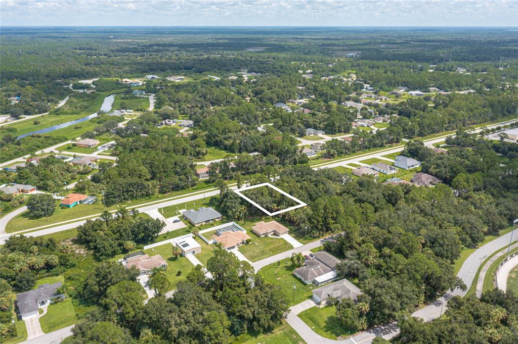 An aerial view shows a vacant, rectangular wooded lot outlined in white within a residential neighborhood — E PRICE BOULEVARD LOT 9, NORTH PORT, FL