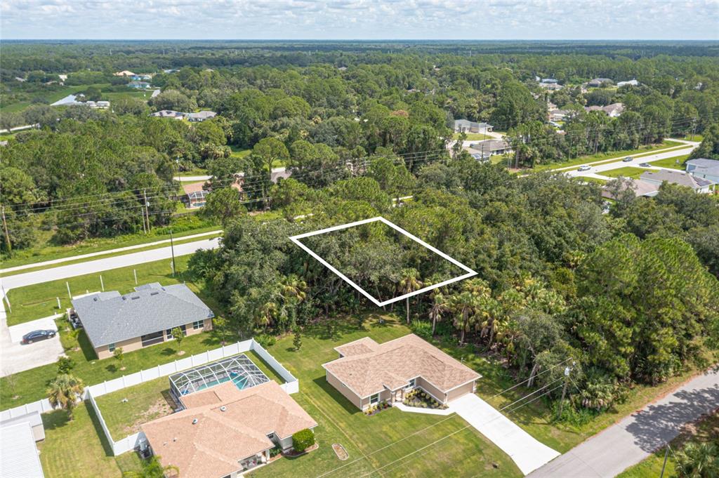 An aerial view shows a vacant, wooded residential lot outlined in white near existing houses — E PRICE BOULEVARD LOT 9, NORTH PORT, FL