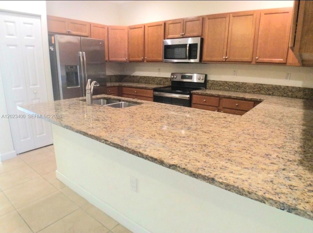 A two-story townhouse exterior features a stone-accented entryway, arched porch, and red tile roof — 9261 W 33rd Way, Hialeah FL 33018, HIALEAH, FL