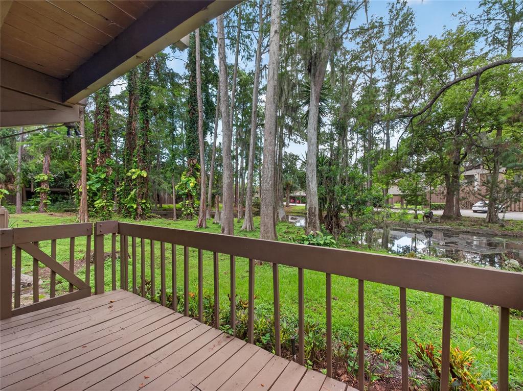 A wooden deck with a railing overlooks a small pond surrounded by trees — 5314 INDIAN CREEK DRIVE UNIT D08, ORLANDO, FL