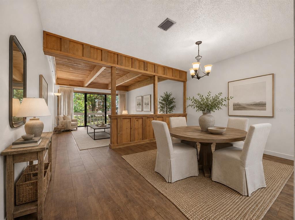 A dining area with a round wooden table and chairs next to a sunken living room — 5314 INDIAN CREEK DRIVE UNIT D08, ORLANDO, FL