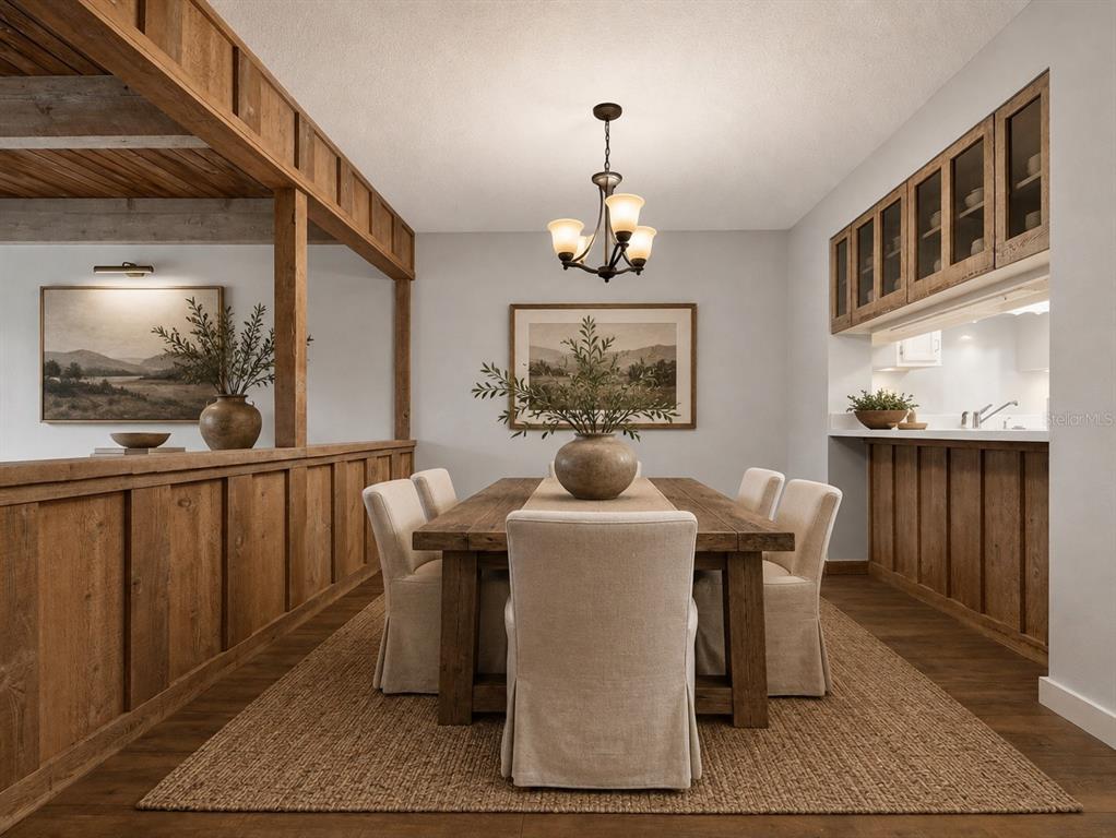 A dining room features a wooden table, upholstered chairs, a chandelier, and rustic wood paneling — 5314 INDIAN CREEK DRIVE UNIT D08, ORLANDO, FL