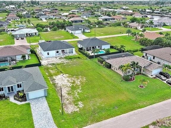 An aerial view shows several suburban houses and a vacant lot in a residential neighborhood — 1025 NW 35TH PLACE, CAPE CORAL, FL