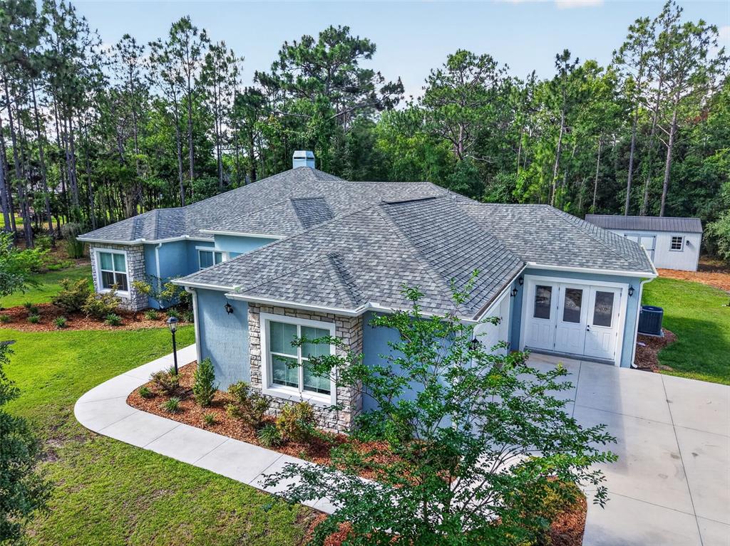 An aerial view of a blue house with a stone facade and a gray roof — 2075 COUNTY ROAD 243F, WILDWOOD, FL